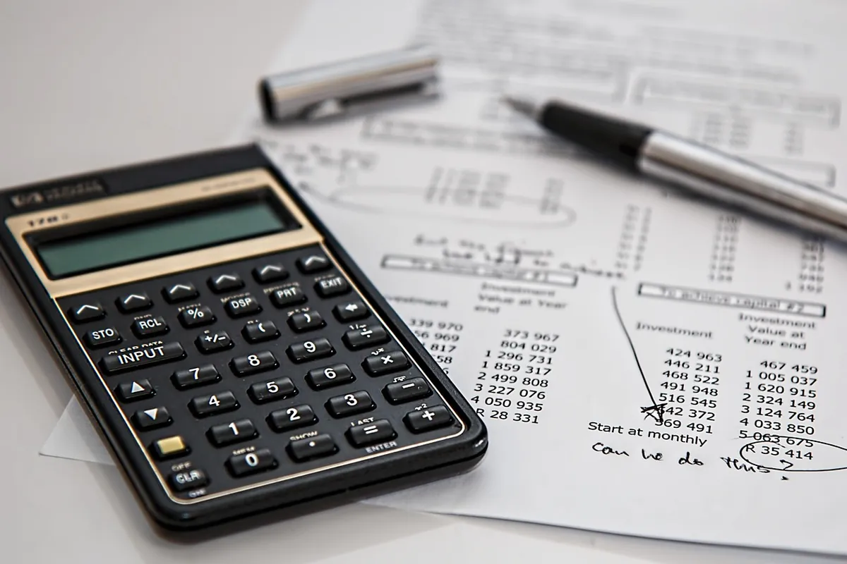 Calculadora, caneta e papéis de orçamento sobre uma mesa