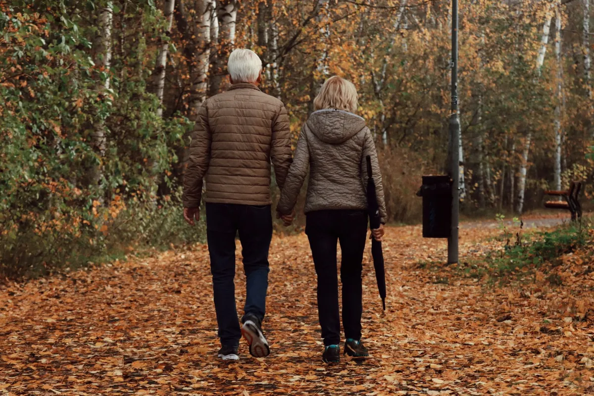 Casal de idosos caminhando de costas por um parque no outono