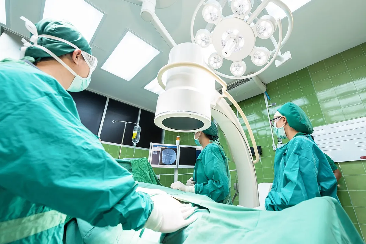 Equipe cirúrgica em sala de operação com arco cirúrgico de radioscopia ao lado da mesa