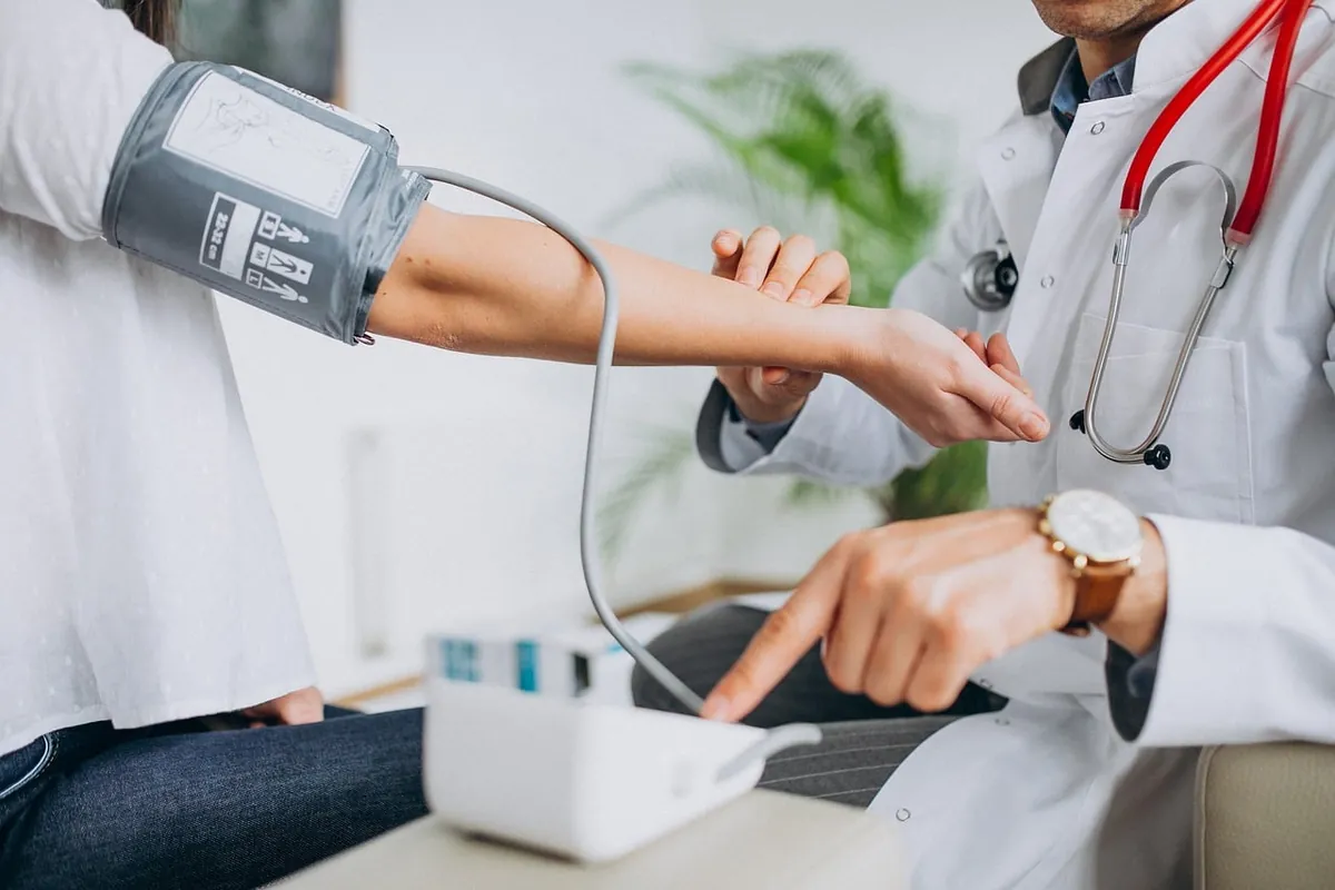 Médica medindo a pressão arterial de um paciente com aparelho digital