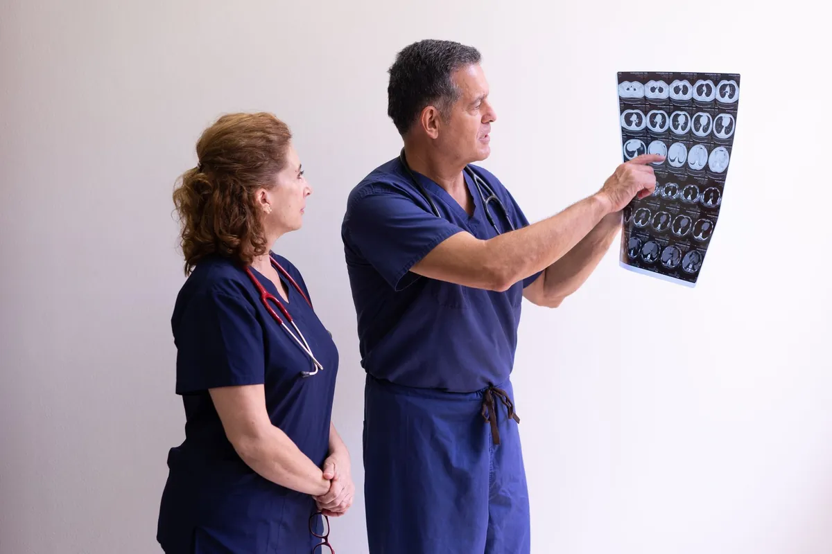 Dois médicos analisando exames de imagem fixados em uma parede