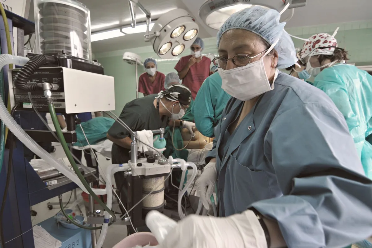 Equipe em uma sala de operação com monitores e equipamentos de anestesia